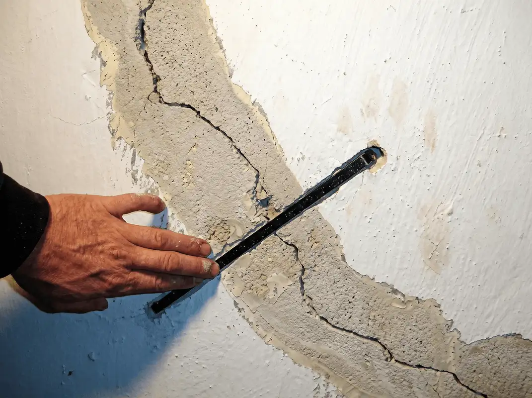 A wall with a large crack is being inspected by a professional in Pembroke Pines, FL