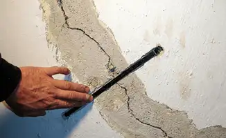 A wall with a large crack is being inspected by a professional in Pembroke Pines, FL